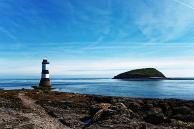 Lighthouse by sea against sky