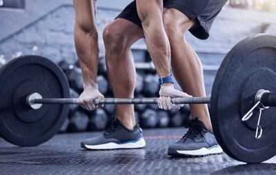 Midsection of man lifting dumbbell in gym