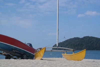 Boats moored on beach against blue sky