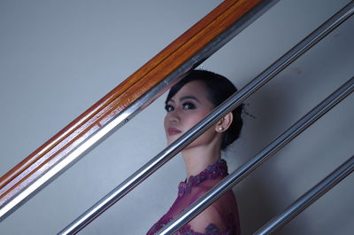 Portrait of young woman standing by railing at home