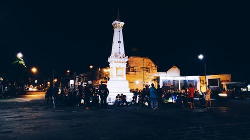 People at illuminated temple against sky at night