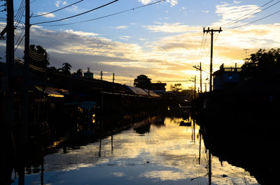 Reflection of silhouette buildings in water at sunset
