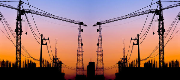 Low angle view of cranes at sunset