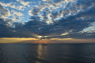 Scenic view of sea against dramatic sky during sunset