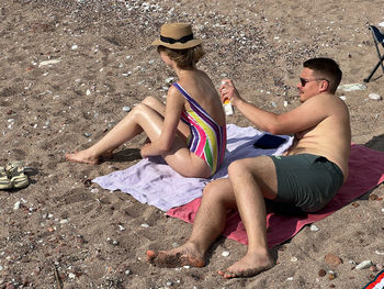 Young woman sitting on sand at beach