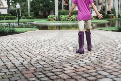 Young girl wearing purple boots walking in driveway