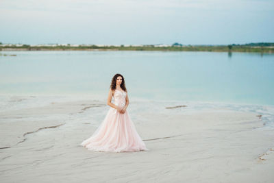 Woman with arms raised on beach against sky