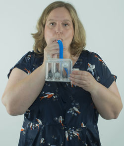 Portrait of young woman drinking glass against white background