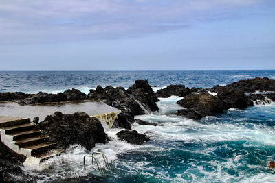 Rocks on sea shore against sky