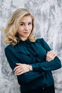 Portrait of beautiful young woman standing against wall