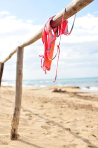 Red wooden post on beach against sky