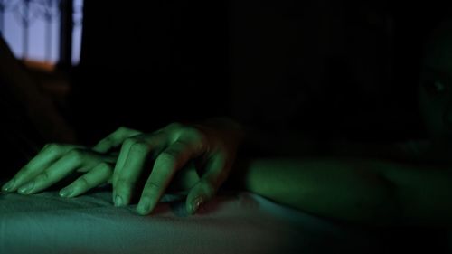 Close-up of person hand on bed at home