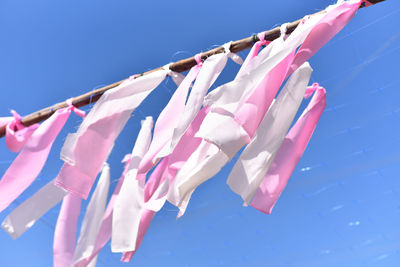 Low angle view of clothespins hanging against blue sky