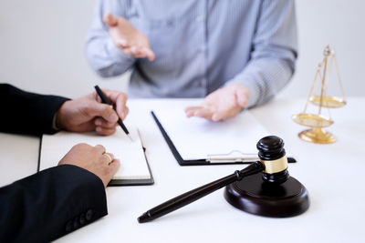 Midsection of man holding hands with coffee cup on table