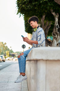 Young man with afro hair smiles while he is using his smartphone