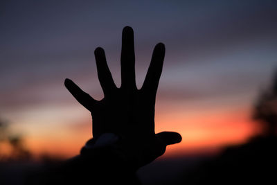 Close-up of silhouette hand against sky during sunset