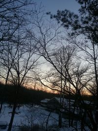 Silhouette trees by lake against sky during sunset