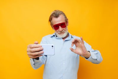 Senior man gesturing while taking selfie