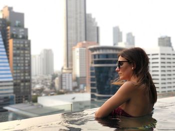 Young woman looking at cityscape against buildings in city