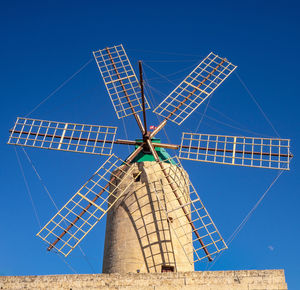 Low angle view of windmill against blue sky