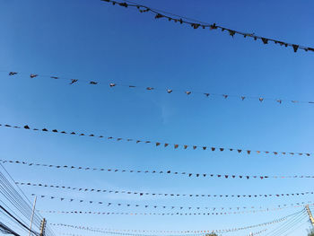 Low angle view of electric line against clear blue sky