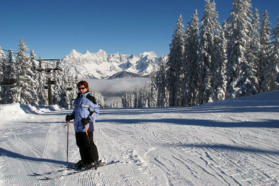 Full length of woman skiing on snow covered landscape during winter