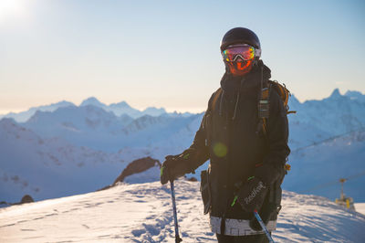 Skier in a fashionable jacket and with a backpack stands on skis against the backdrop of the