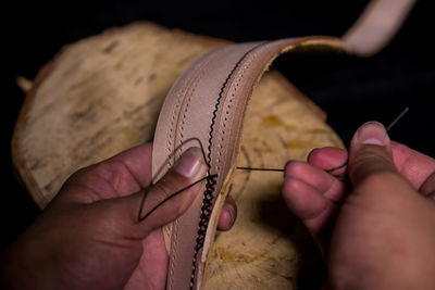 Close-up of craftsperson making belt in workshop