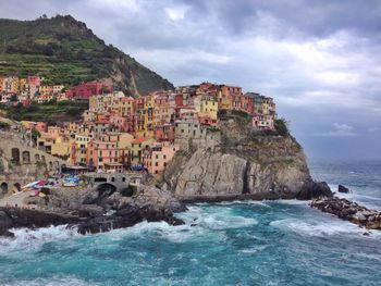 View of houses in front of sea against cloudy sky