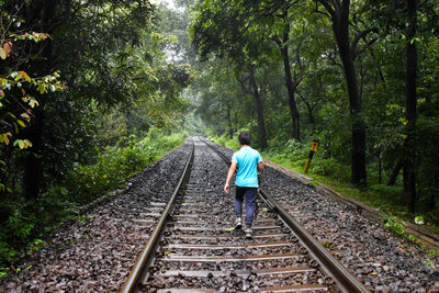 Rear view of boy walking on railroad track