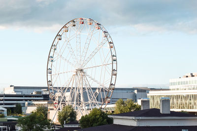 Ferris wheel by buildings in city against sky