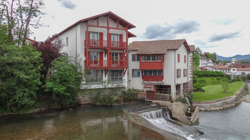 Houses by river amidst buildings against sky