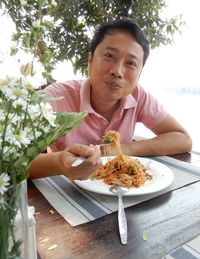 Portrait of man eating food on table in restaurant