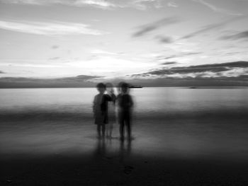 People standing on beach against sky