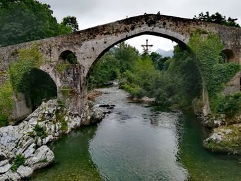Arch bridge over river against sky