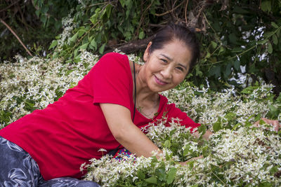 Portrait of smiling woman by flowering plants