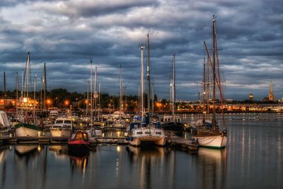 Boats moored at illuminated port during sunset against sky