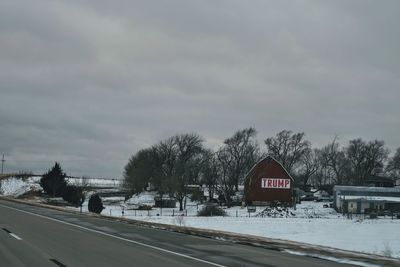 Road by trees against sky during winter