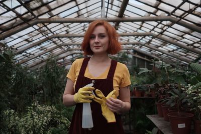 Portrait of beautiful young woman standing in greenhouse