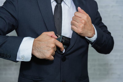 Midsection of businessman inserting handgun in blazer