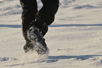 Man walking on snow with shoe spikes in winter time