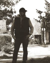 Young man looking away while standing against trees