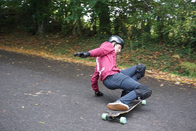 Full length of man falling while skateboarding on road