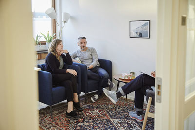 Man and woman talking to counselor while sitting at workshop