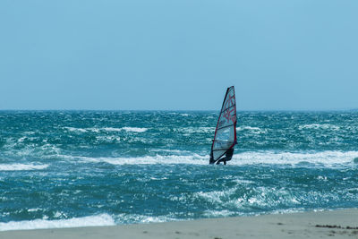 Person windsurfing against clear sky