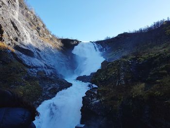 Scenic view of waterfall against clear blue sky