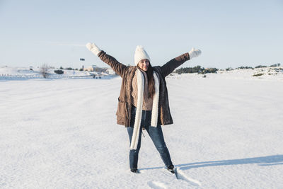 Woman with arms outstretched on snow covered land
