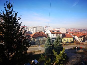 High angle view of buildings and trees against blue sky