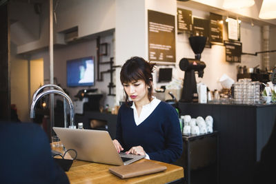 Confident female entrepreneur using laptop sitting at table in office