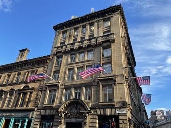 Low angle view of building against blue sky with usa flags for indiana jones movie filming glasgow